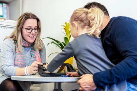 Beratungsgespräch beim Allgemeinen Sozialen Dienst: Sozialarbeiterin mit Brille und zwei Personen besprechen Unterlagen an einem Tisch. Vertrauliche Unterstützung bei Familien- und Erziehungsfragen.