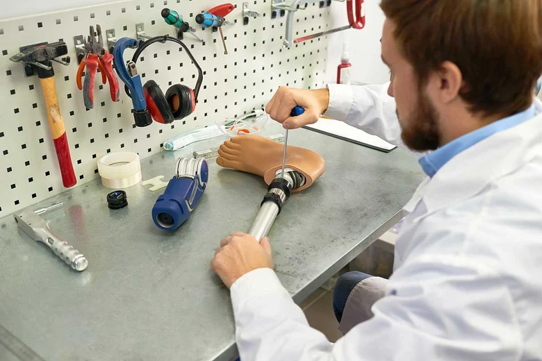 Orthopädiemechanikerin passt Beinprothese in Werkstatt an. Orthopädiemechaniker fertigen Prothesen, Orthesen und Hilfsmittel nach Maß, passen sie individuell an und verbessern so Mobilität und Lebensqualität von Menschen mit körperlichen Einschränkungen.
