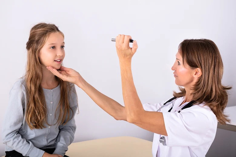 Ärztin führt orthoptische Untersuchung bei Mädchen durch und hält Untersuchungsinstrument vor das Auge des Kindes.